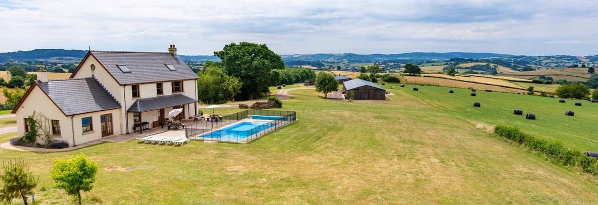 Modern country house with swimming pool overlooking rolling pastoral farmland and distant hills